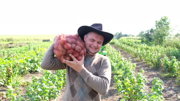 A Young Farmer Holds a Bag of Dug Potatoes