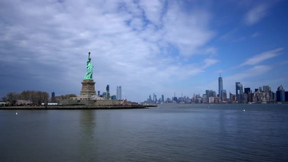 Statue of liberty island with New York City skyline in background across water