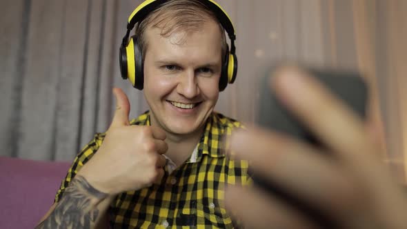 Young Man Making Selfie, Talking, Video Call at Home in Wireless Headphones