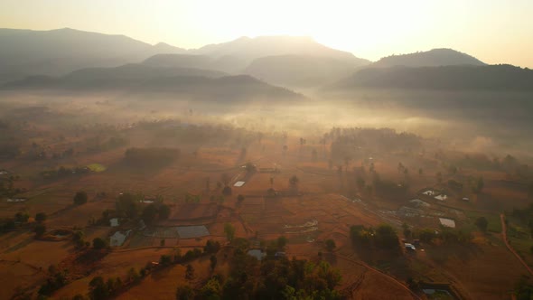 Aerial view over villages and barren fields in countryside during sunrise