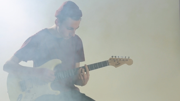 Guy In Hat Playing Guitar In The Studio In Smoke