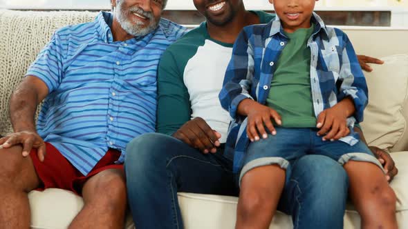 Smiling multi-generation family sitting together on sofa