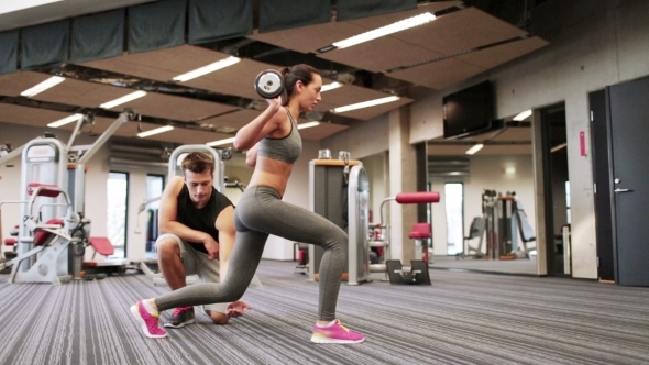 Man And Woman With Barbell Flexing Muscles In Gym