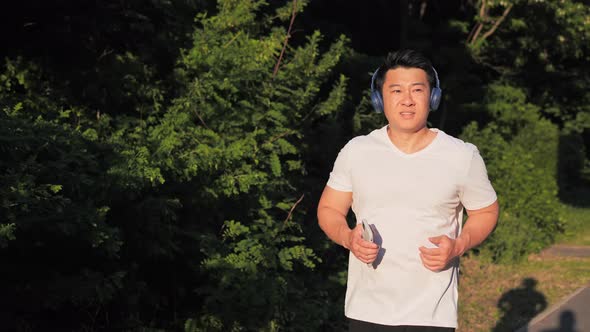 Asian Sportsman Jog Cardio Workout at Sunset Listening to Music
