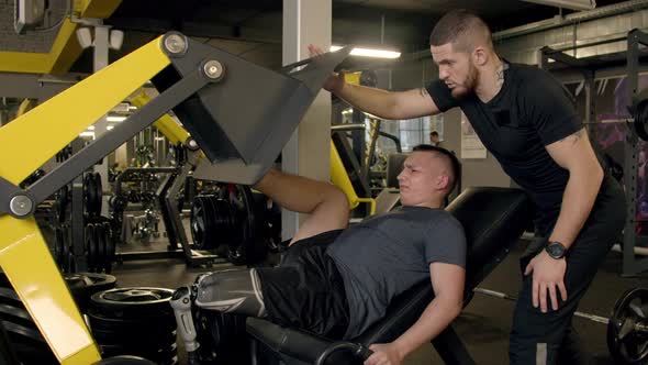 Young Man with Prosthetic Leg Using Leg Press Machine in Gym