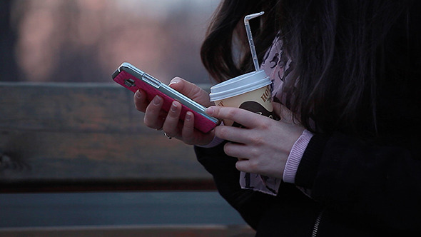 Female Hands Typing Sms and Keeps Coffee alt