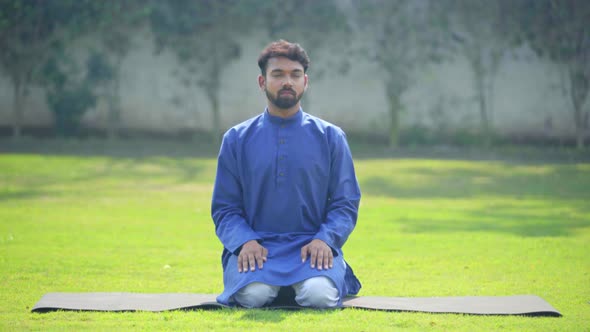 Indian man doing Vajrasana or Thunderbolt Yoga Pose or Diamond Yoga Pose in Kurta Pajama