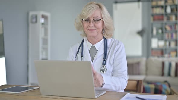 Thumbs Up By Old Female Doctor Working on Laptop