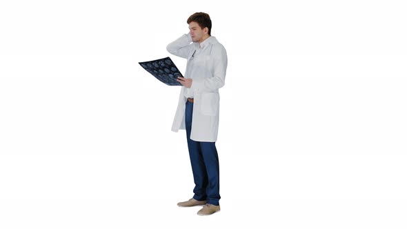 Frustrated Male Doctor Examining Computed Tomography Scan of Brain on White Background.