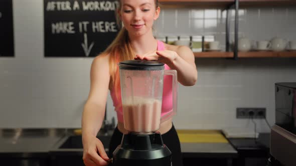 Female athlete making a protein shake in a blender