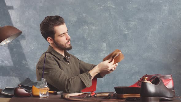 Young Bearded Cobber Holding a Set of Cloth for Footwear