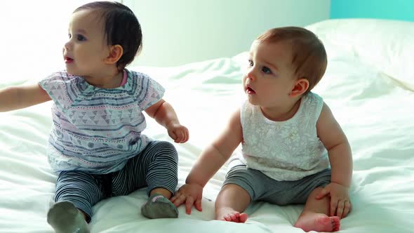Two cute baby girls sitting on bed