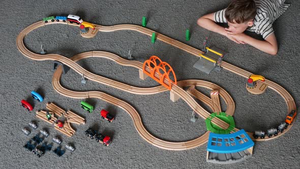 Boy is playing with toy railway and is watching train crash