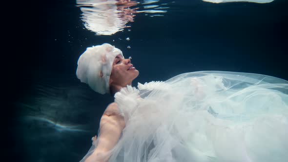 Charming Woman in White Gown is Floating in Water of Magical Sea or Ocean Fabulous Fairy