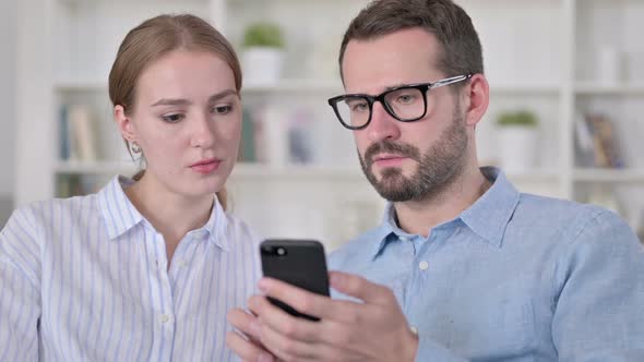 Portrait of Serious Young Couple Using Smartphone Together