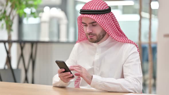 Attractive Arab Businessman Using Smartphone in Office