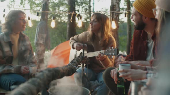Girls Playing Guitar and Singing by Campfire