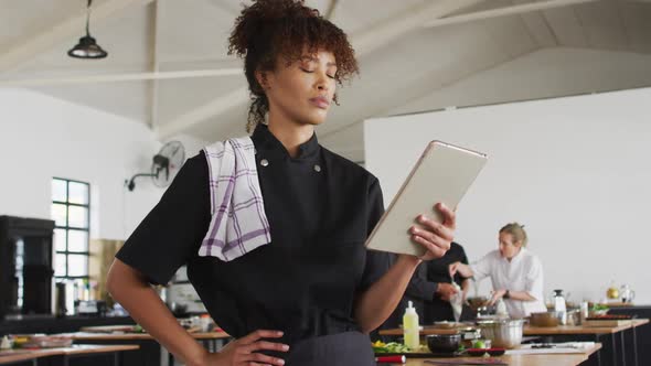 Mixed race female chef using digital tablet