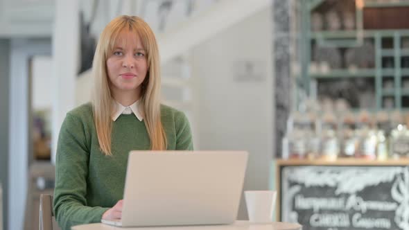 Young Woman Showing Thumbs Up Sign While Working on Laptop in Cafe