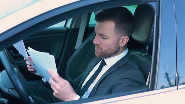 Portrait of a Confident Man Sitting in a Car with Documents in a Business Suit Near a Modern Office
