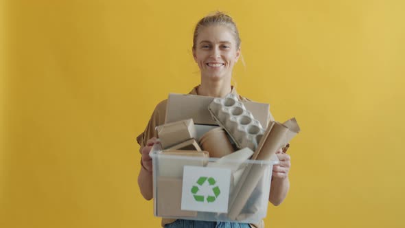 Portrait of Young Woman Holding Box of Cardboard Trash with Recycling Symbol