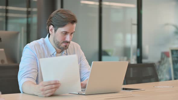 Man with Laptop Having Success Reading Documents