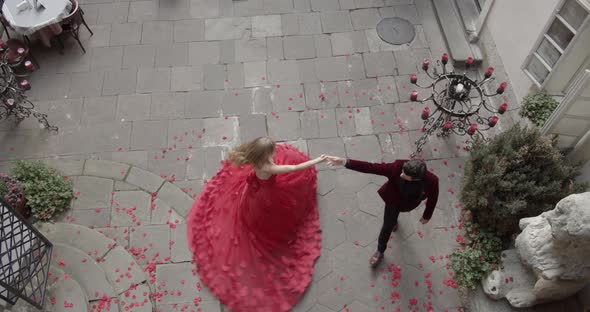 A Girl In A Ball Gown And A Guy In A Suit Dancing And Flower Petals Falling From Above