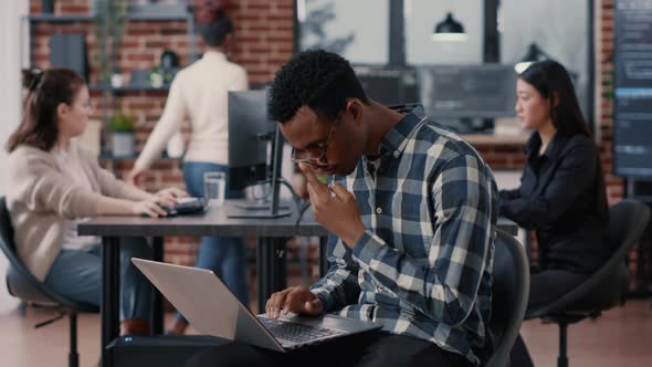 Portrait of Artificial Intelligence App Developer Sitting Down Typing on Laptop Fixing Glasses