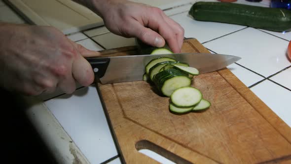 Close-Up Of Man Chopping Courgette In Kitchen