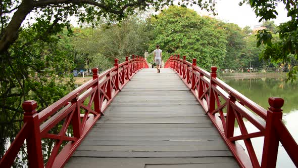 Vietnamese Woman Walking Over The Huc Bridge On Hoan Kiem Lake In Hanoi Vietnam