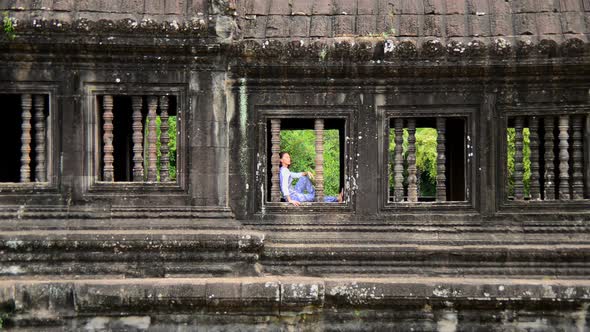 Female Buddhist Meditating In Window - Angkor Wat, Cambodia alt