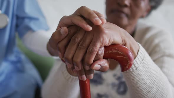 Close up of american african female doctor and senior patient holding hands