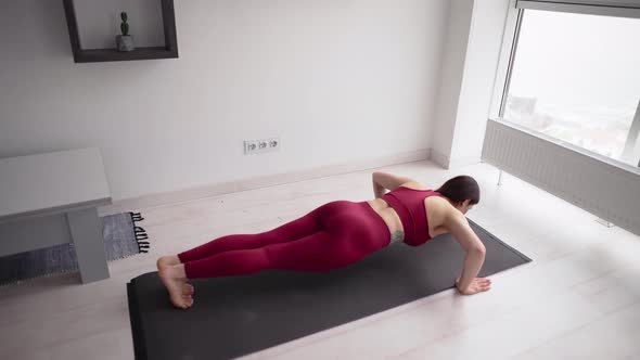 Young Sporty Woman is Doing Pushups Exersice in Front Home Window