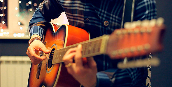 Man Playing an Acoustic Guitar on a Beautiful Back