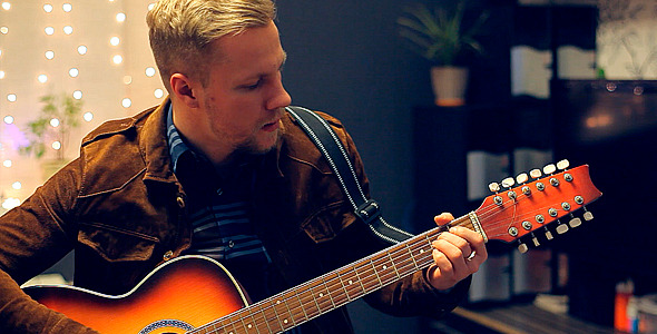 Man Playing an Acoustic Guitar on a Beautiful Back alt