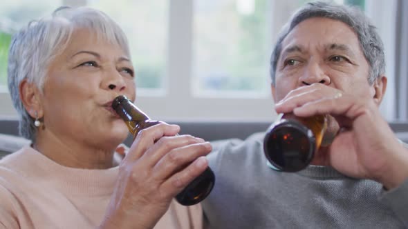 Happy mixed race senior couple drinking beer and having fun