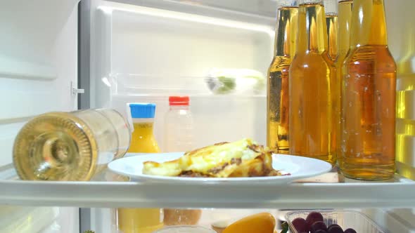 Woman Taking Plate Of Iced Cupcakes From The Fridge