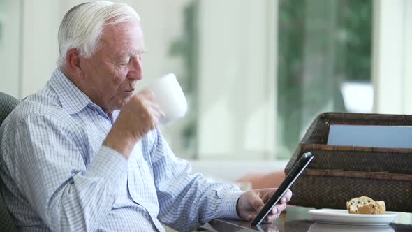 Senior Man Using Digital Tablet Sitting At Desk 2 alt