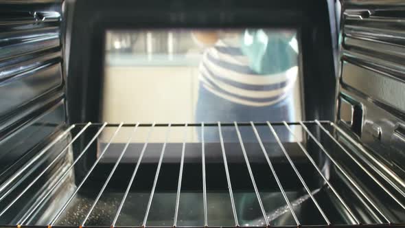 Woman Taking Tray Of Baked Muffins Out Of The Oven