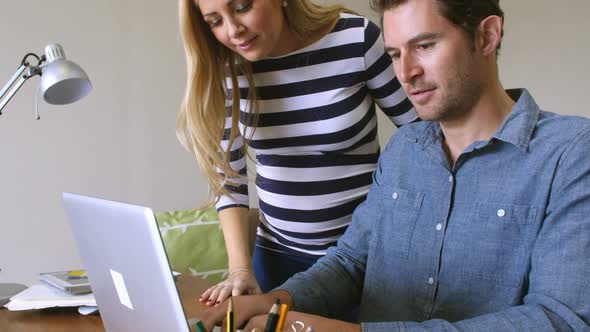 Expectant Couple Sitting At Computer Shopping On Line