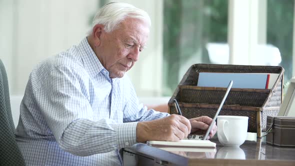 Senior Man Using Laptop On Desk At Home