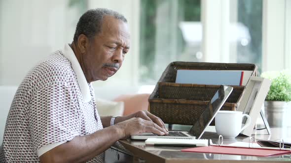 Senior Man Using Laptop Sitting At Desk alt