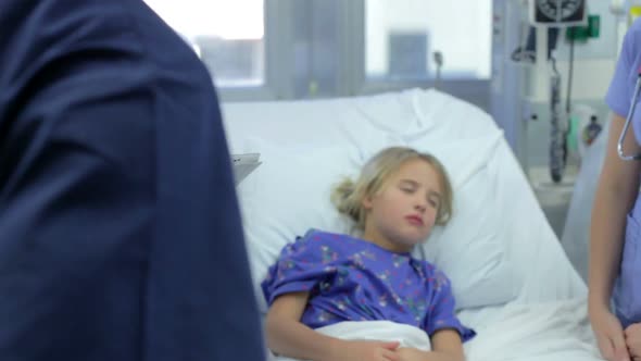 Staff In Emergency Room Meeting Around Young Girl's Bed
