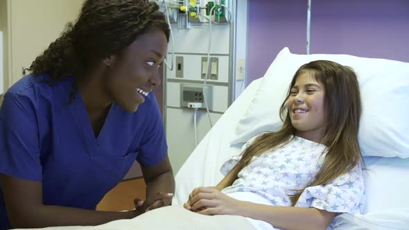 Young Girl Talking To Female Nurse In Hospital Room