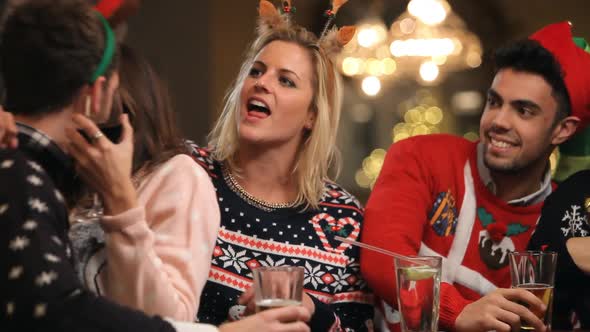 Couple Kissing In Bar As Friends Enjoy Christmas Drinks 1