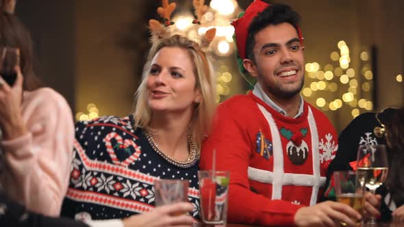 Couple Kissing In Bar As Friends Enjoy Christmas Drinks 2