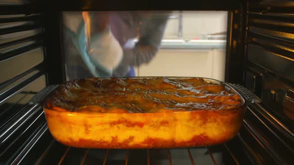 Man Taking Cooked Dish Of Lasagne Out Of The Oven