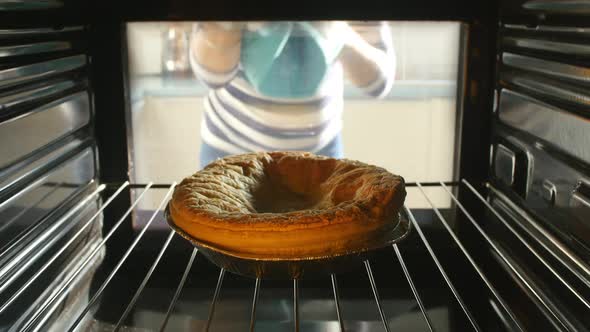 Woman Putting Savory Pie Into Oven To Bake