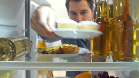 Man Taking Plate Of Iced Cupcakes From The Fridge