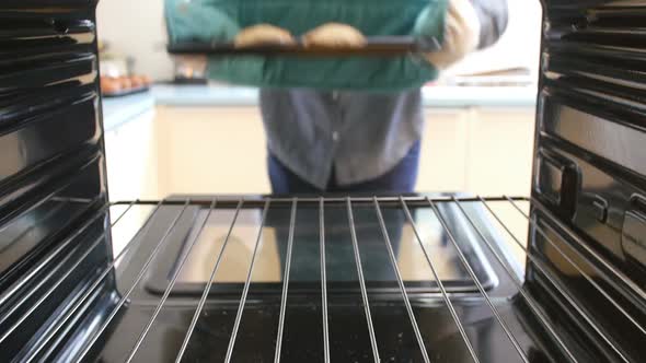 Man Taking Tray Of Cooked Stuffed Mushrooms Out Of The Oven